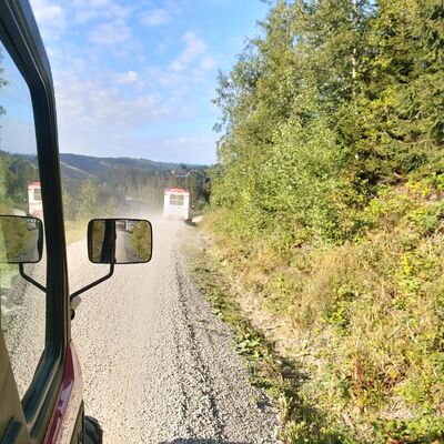 Bild vergr&ouml;&szlig;ern: Das Bild zeigt zwei Autos, die einen unbefestigten Weg befahren.