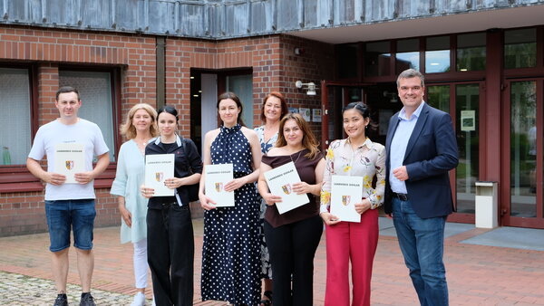 Bild vergr&ouml;&szlig;ern: Gruppenfoto vor dem Kreishaus: Landrat Dr. Alexander Saipa (rechts) gemeinsam mit den eingeb�rgerten Personen und zwei Mitarbeiterinnen aus der Ausl�nderbeh�rde.
